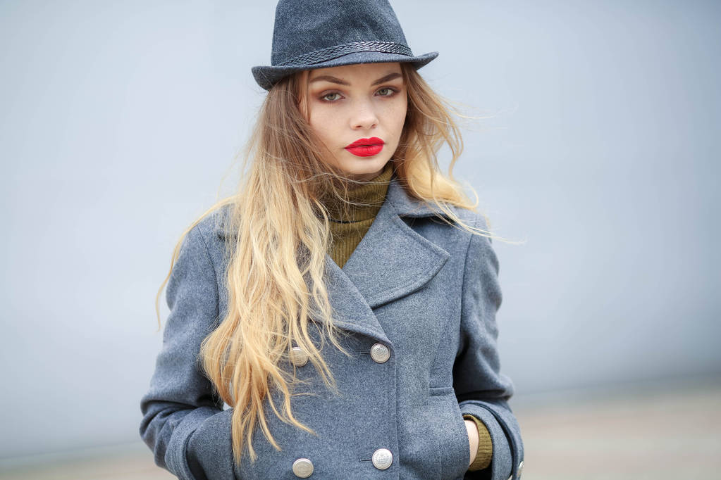 retrato ao ar livre de bela mulher loira vestindo chapéu e casaco cinza
  - Foto, Imagem
