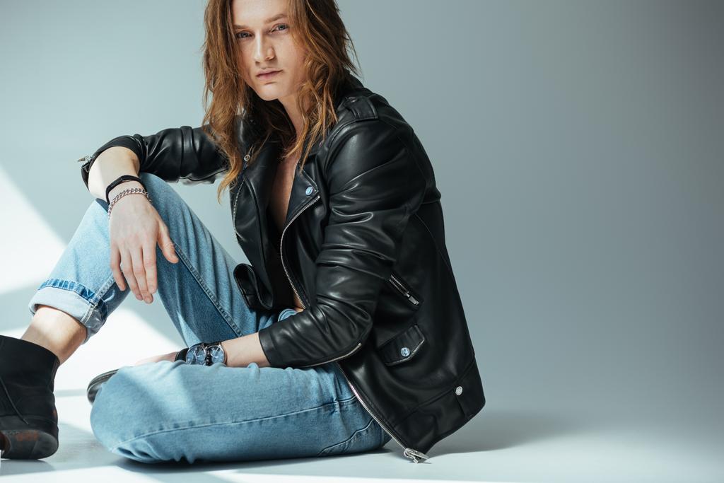 handsome man posing in jeans and black leather jacket, on grey - Photo, Image
