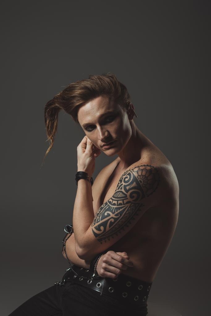 félmeztelen férfi furcsa frizura és a tetoválás a kezében, szürke elszigetelt - Fotó, kép