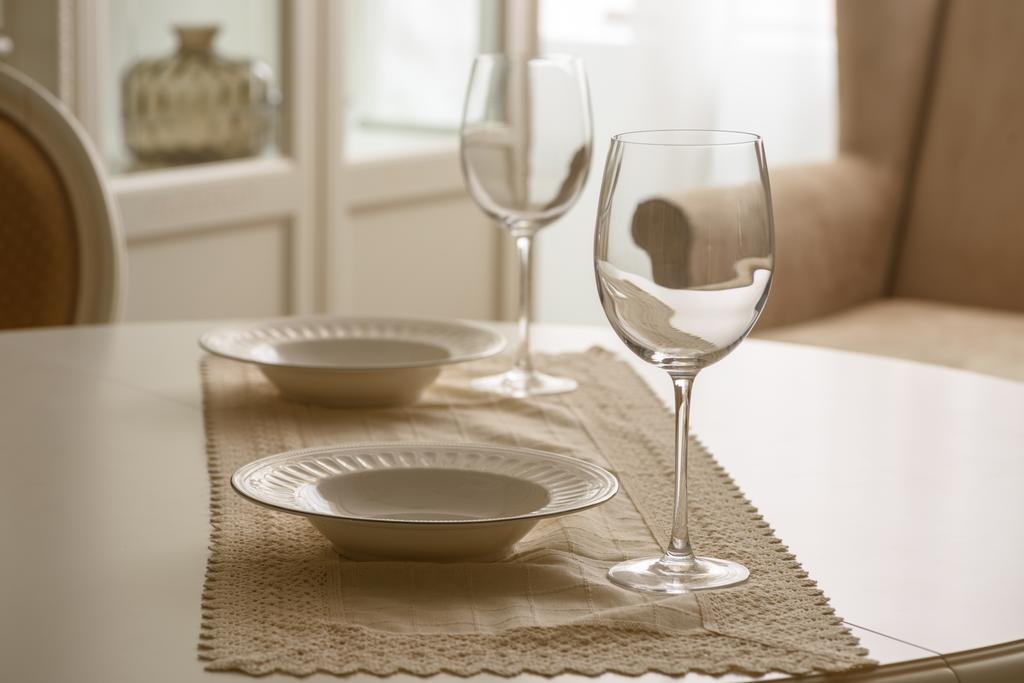 Бокалы и белые тарелки на столе в столовой
 - Фото, изображение