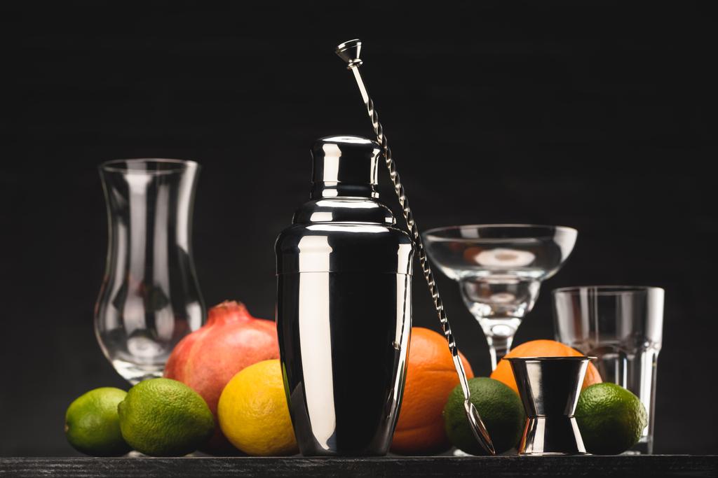 agitador para la preparación de bebidas alcohólicas y vasos vacíos en la mesa aislado en negro
 - Foto, Imagen