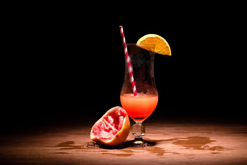 alcohol cocktail met schijfje sinaasappel- en geperst grapefruit op tafel - Foto, afbeelding