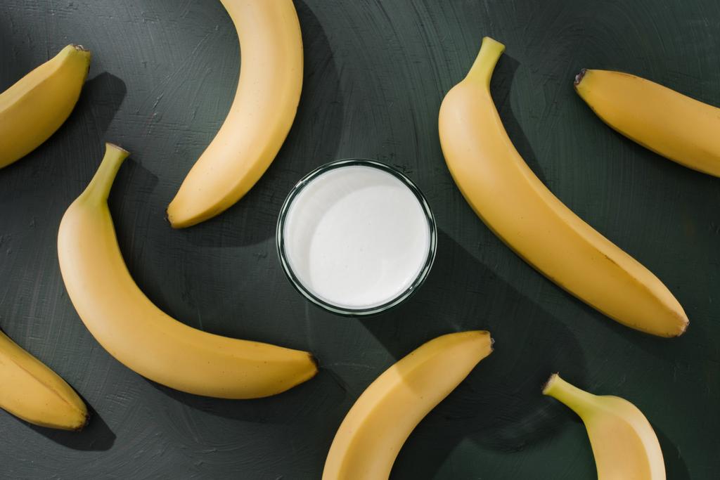 vista superior de vidro com milkshake cercado por bananas na mesa
  - Foto, Imagem