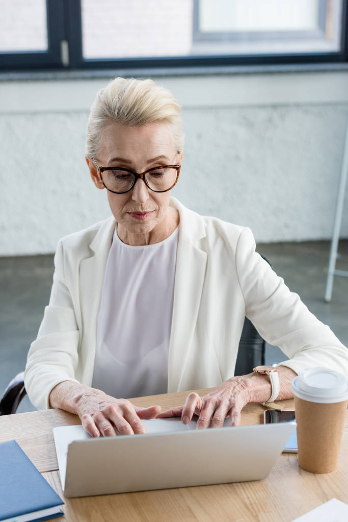mulher de negócios focada em óculos usando laptop no local de trabalho
 - Foto, Imagem
