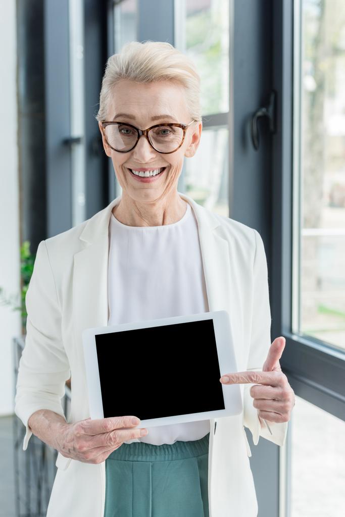 podnikatelka v brýle drží digitální tablet s prázdnou obrazovkou a usmívá se na kameru - Fotografie, Obrázek