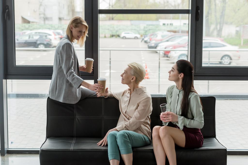 beautiful businesswomen with coffee in paper cups during coffee break in office - Photo, Image