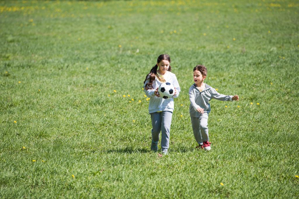 fratello e sorella giocare a calcio su prato erboso
  - Foto, immagini