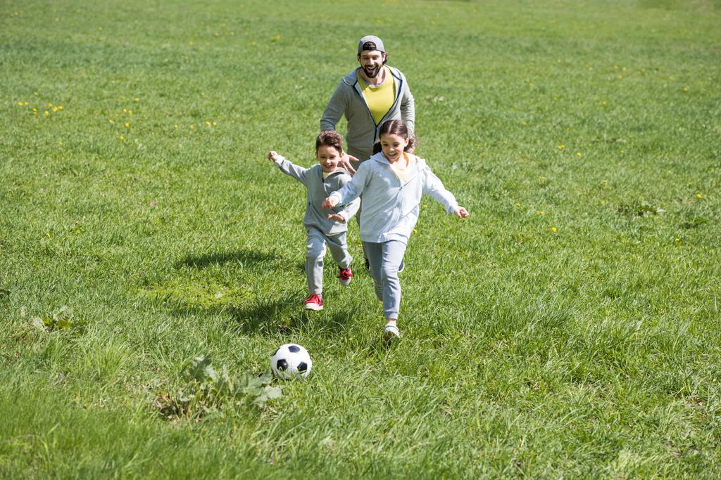pai jogando futebol com filha e filho no parque
 - Foto, Imagem