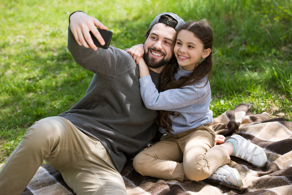sorrindo pai tomando selfie com filha em xadrez no parque
 - Foto, Imagem