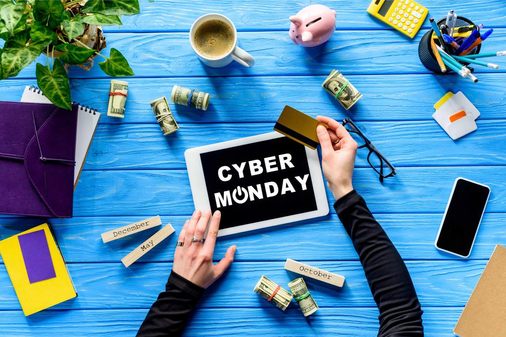 Руки проведення планшет і кредитну картку на синій дерев'яний стіл з грошима, кібер понеділок написи  - Фото, зображення