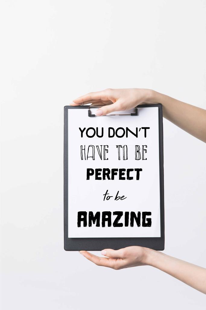 partial view of woman holding clipboard with "You dont have to be perfect to be Amazing" inspiration, isolated on white  - Photo, Image