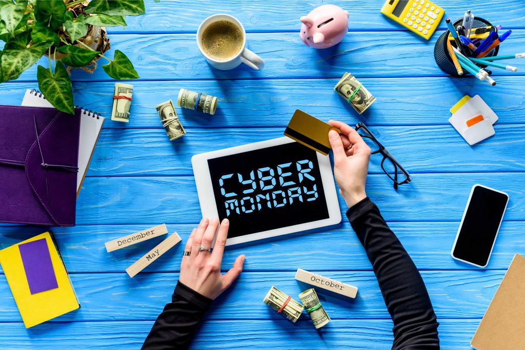 Mãos segurando tablet e cartão de crédito na mesa de madeira azul com dinheiro, letras Cyber segunda-feira
  - Foto, Imagem