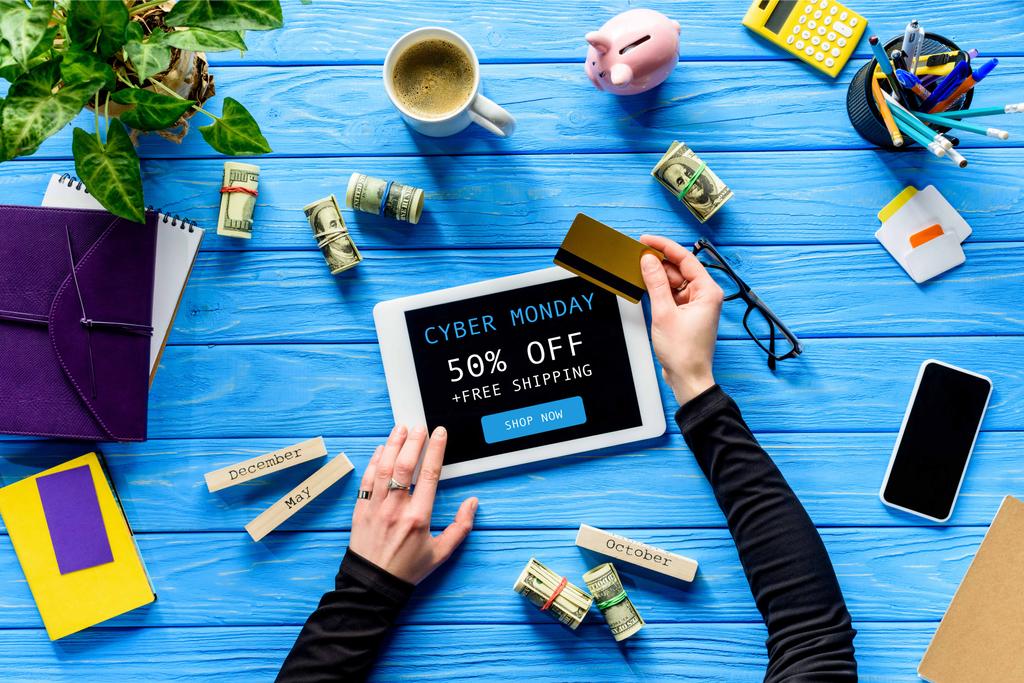 Mains tenant tablette et carte de crédit sur table en bois bleu avec de l'argent, Cyber lundi, lettrage livraison gratuite
  - Photo, image
