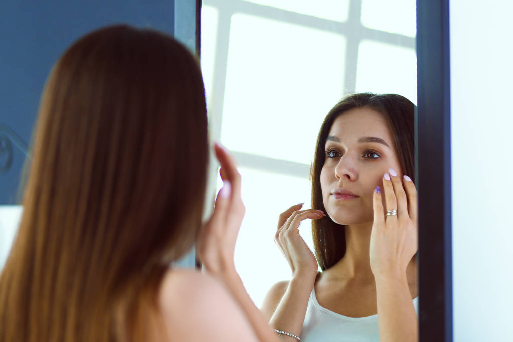 Jeune femme se regardant réflexion dans le miroir à la maison
 - Photo, image