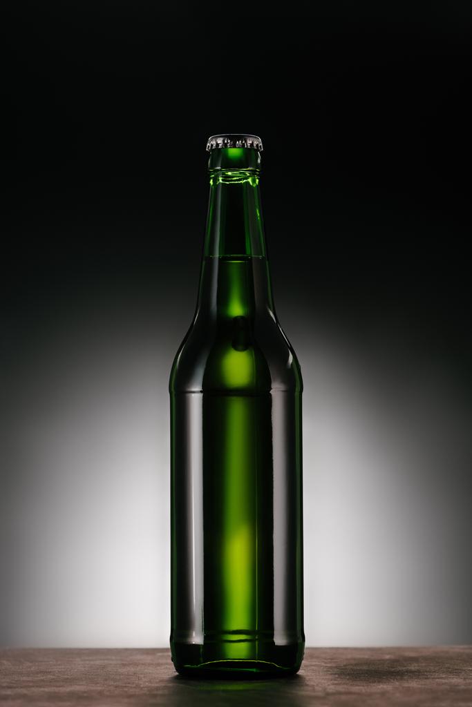 Nahaufnahme einer Bierflasche vor dunkelgrauem Hintergrund - Foto, Bild