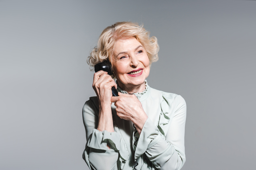 lähikuva muotokuva hymyilevä vanhempi nainen puhuu vintage puhelin eristetty harmaa
 - Valokuva, kuva