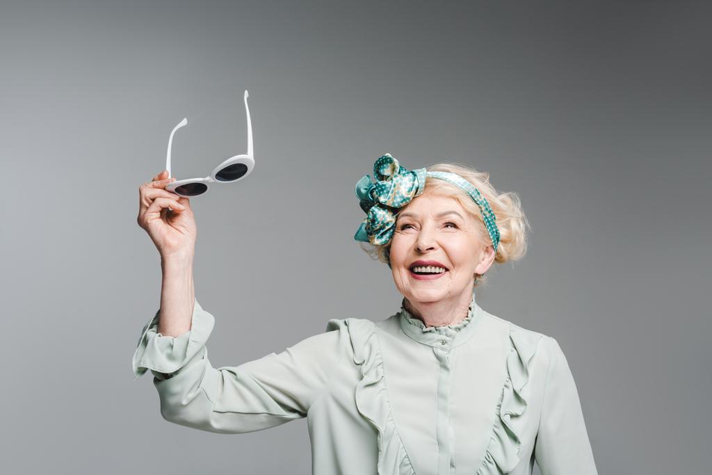 Stylový starší žena držící retro brýle izolované Grey - Fotografie, Obrázek