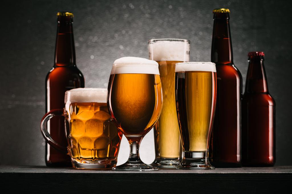 close up view of bottles and mugs of beer on grey background - Photo, Image