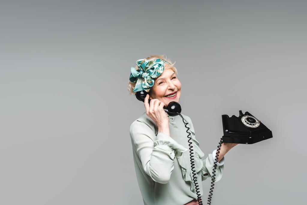 mujer mayor con estilo hablando por teléfono giratorio aislado en gris
 - Foto, Imagen