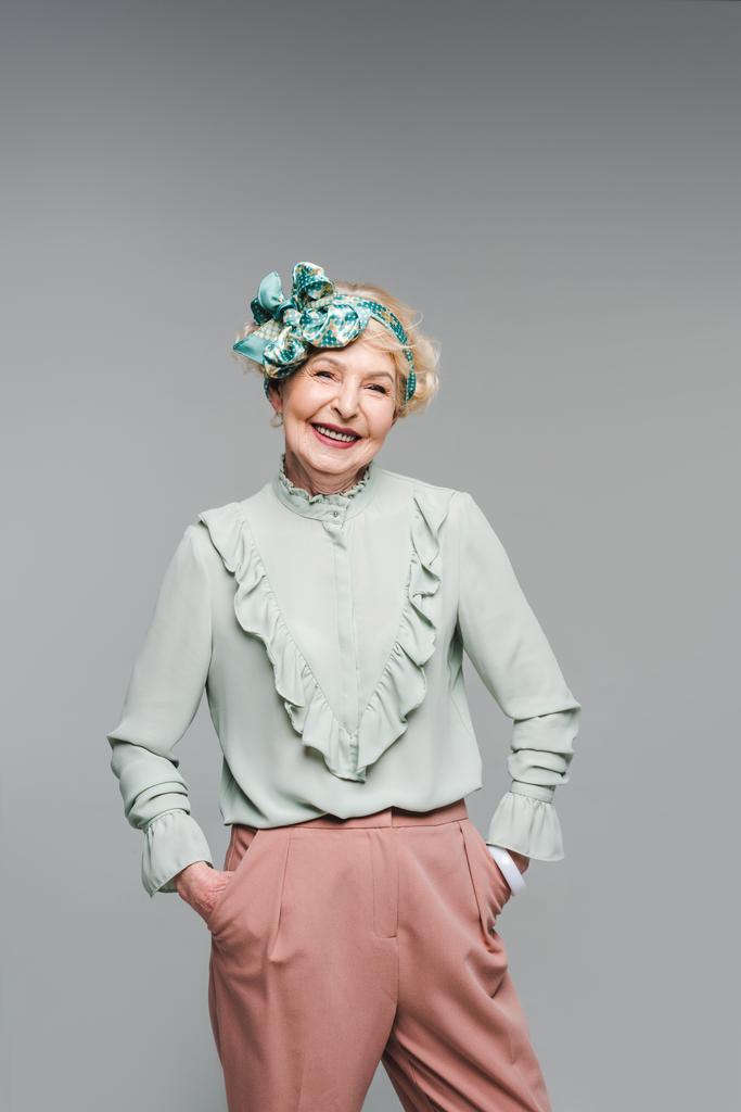 улыбающаяся пожилая женщина в стильной одежде, смотрящая на камеру, изолированную на сером
 - Фото, изображение