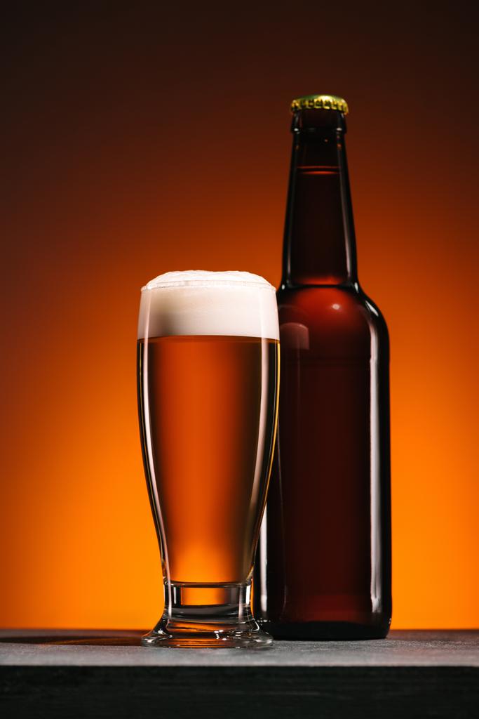 zblízka pohled na láhve a džbánek piva na oranžové pozadí - Fotografie, Obrázek
