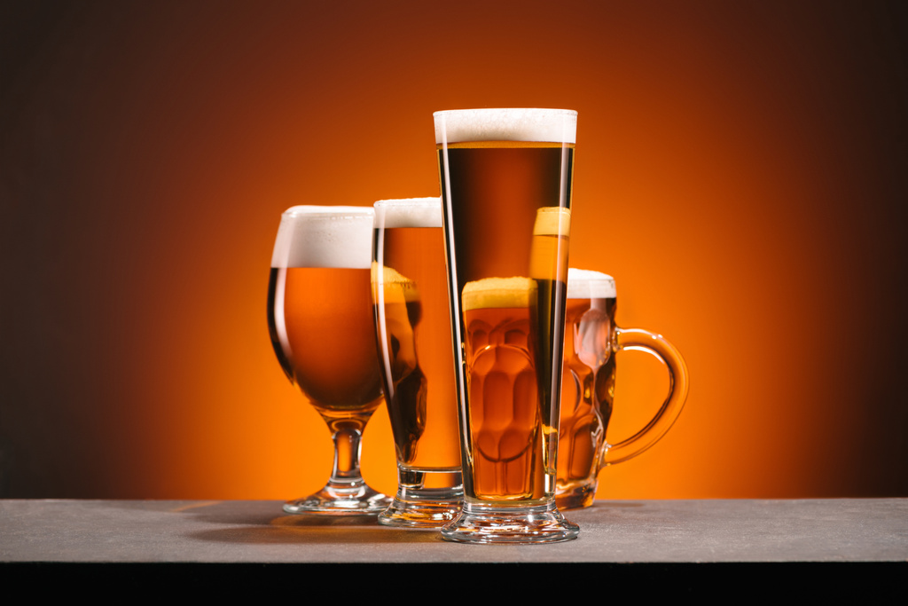 Nahaufnahme der Anordnung von Biergläsern auf orangefarbenem Hintergrund - Foto, Bild