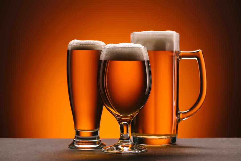 Zamknij widok układu szklanek piwa na pomarańczowym tle - Zdjęcie, obraz