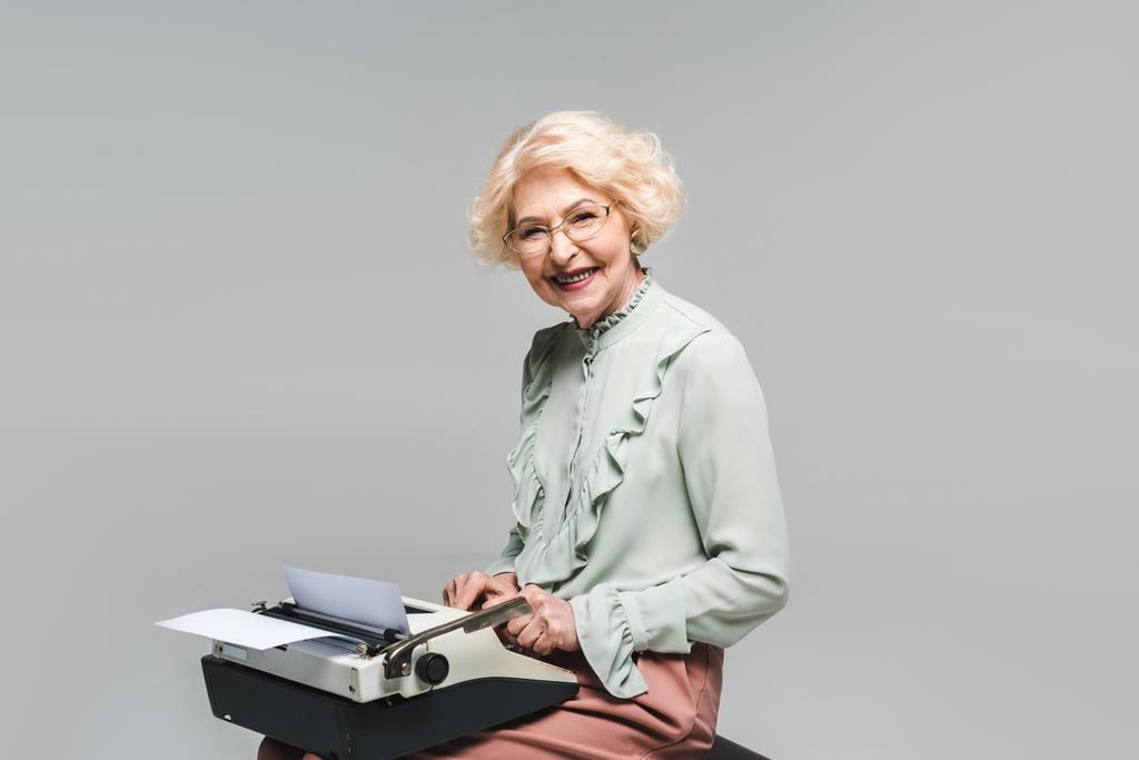 heureux senior femme en utilisant machine à écrire sur gris
 - Photo, image