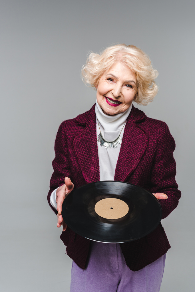 стильная пожилая женщина держит виниловый диск изолирован на сером фоне
  - Фото, изображение