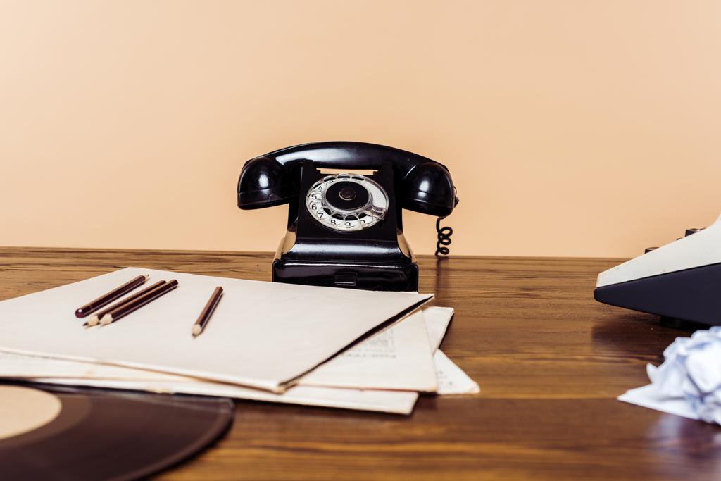 крупним планом знімок ротаційного телефону на дерев'яному столі з друкарською машинкою і вініловим диском на столі
  - Фото, зображення