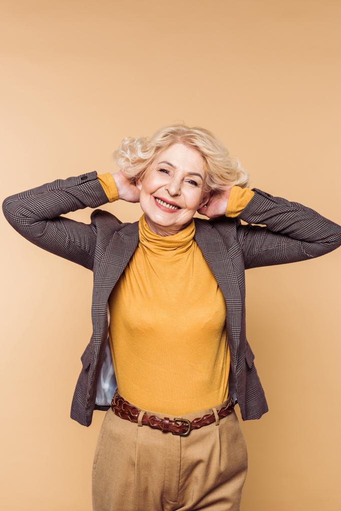 Gelukkig stijlvolle senior vrouw poseren geïsoleerd op beige achtergrond  - Foto, afbeelding