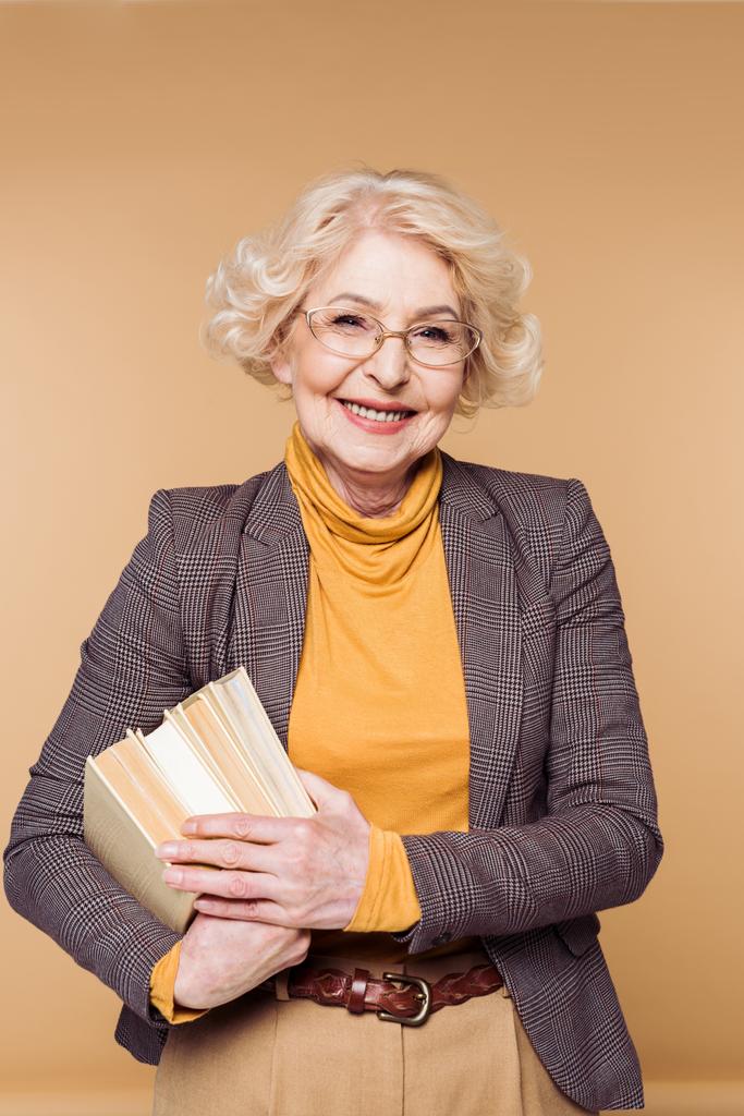χαμογελώντας κομψή ανώτερων γυναίκα σε γυαλιά κρατώντας στοίβα από βιβλία - Φωτογραφία, εικόνα
