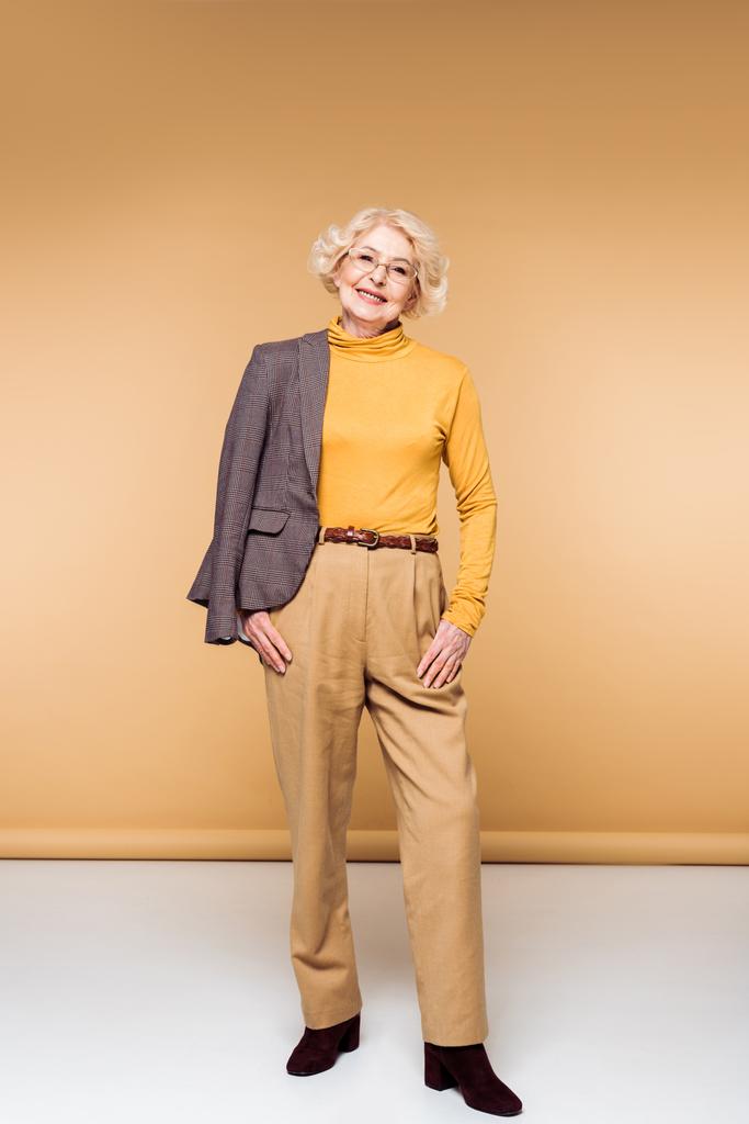 souriant femme âgée à la mode dans des lunettes posant avec veste sur l'épaule
  - Photo, image