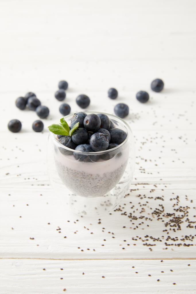 Nahaufnahme von süßem Chiasamen-Pudding mit Blaubeeren und Minze auf weißer Holzoberfläche - Foto, Bild