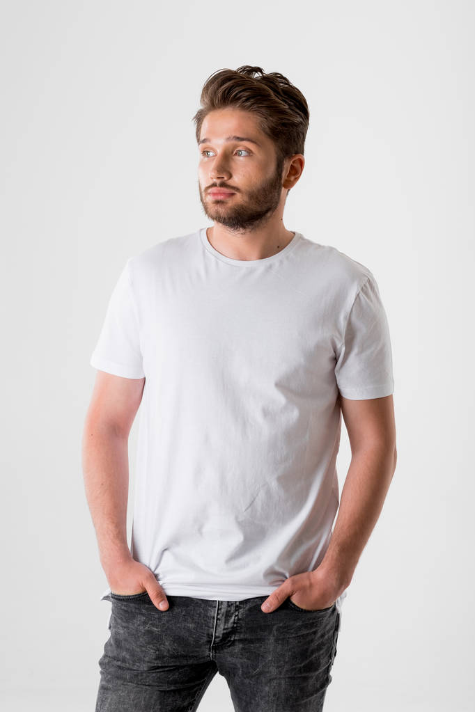 Portret van jonge bebaarde man in wit overhemd op grijze achtergrond  - Foto, afbeelding