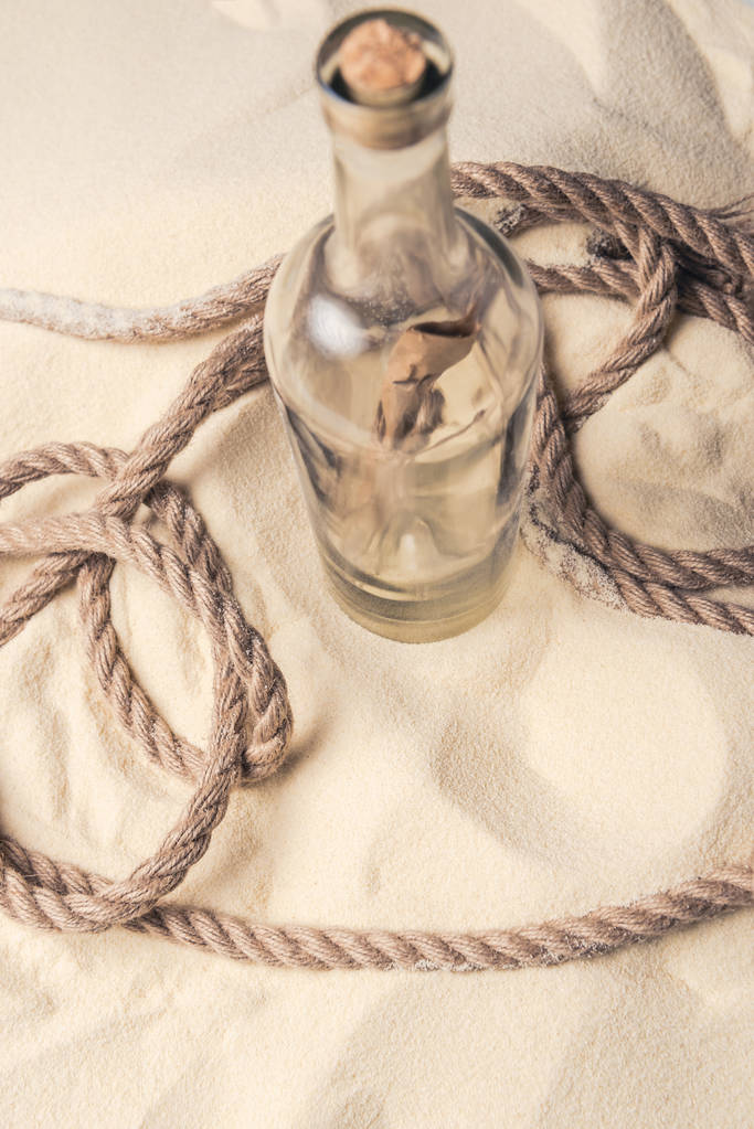 Bottiglia con lettera e corda su sabbia chiara
 - Foto, immagini