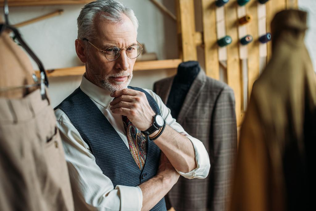 schöner älterer Mann schaut sich Jacken auf Kleiderbügeln im Geschäft an - Foto, Bild