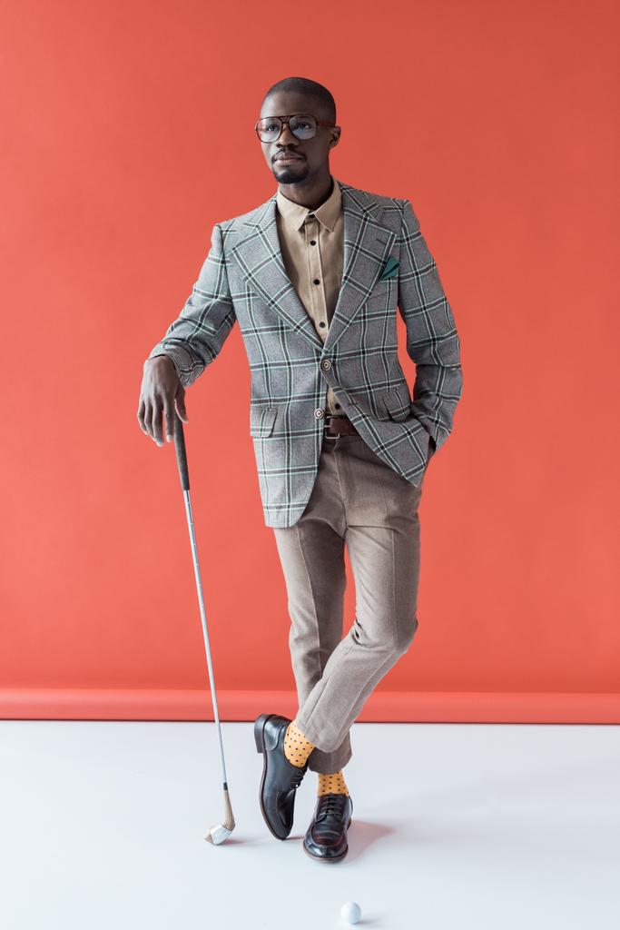 golfista afroamericano alla moda con mazza da golf e palla, su rosso
 - Foto, immagini