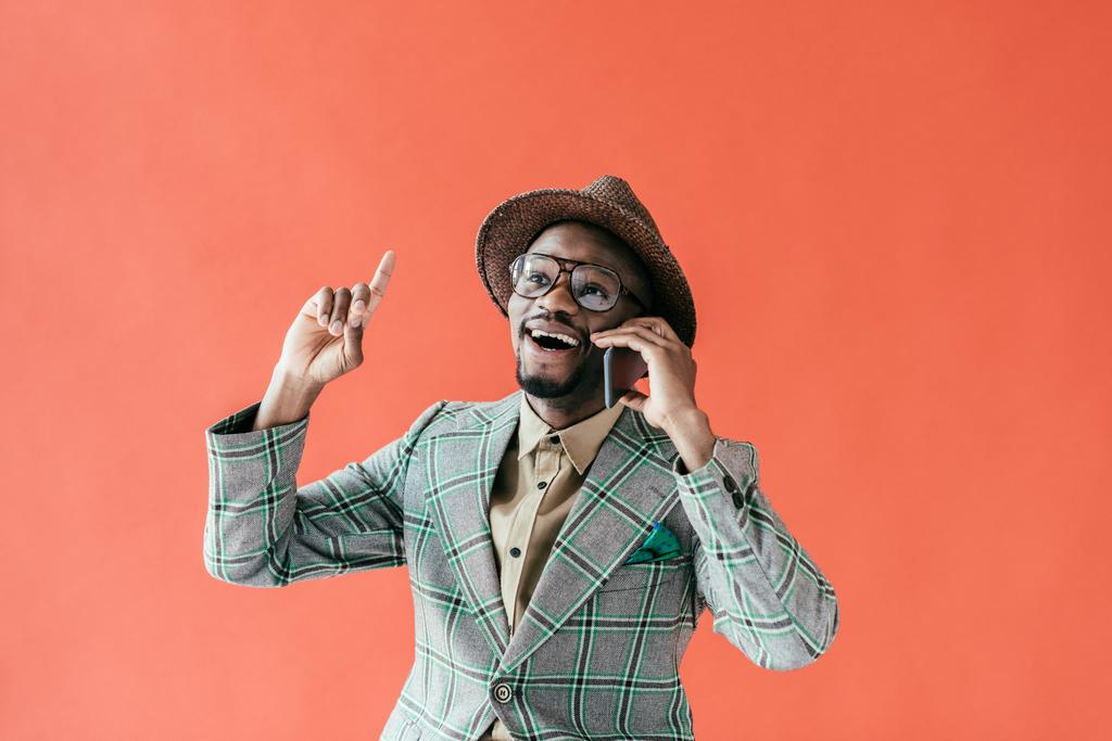 excité homme afro-américain parler sur smartphone et pointant vers le haut avec l'idée, isolé sur rouge
  - Photo, image