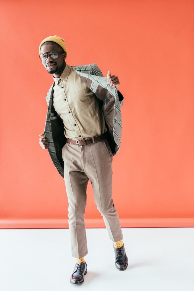 uomo afroamericano in giacca vintage alla moda, su rosso
 - Foto, immagini