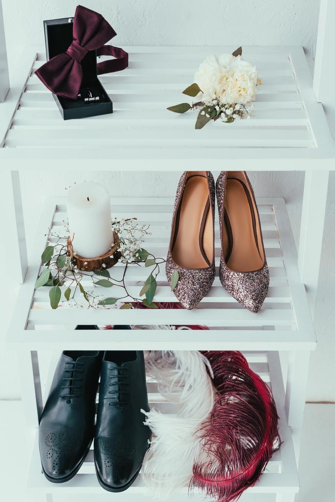close up view of bridal and grooms shoes, candle and decorative feathers on grey backdrop - Photo, Image