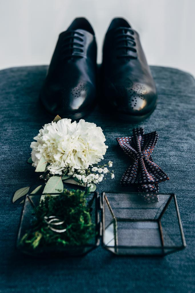vista de cerca de la disposición de los zapatos de novio, pajarita, ramillete y anillos de boda para la boda rústica sobre fondo azul
 - Foto, imagen