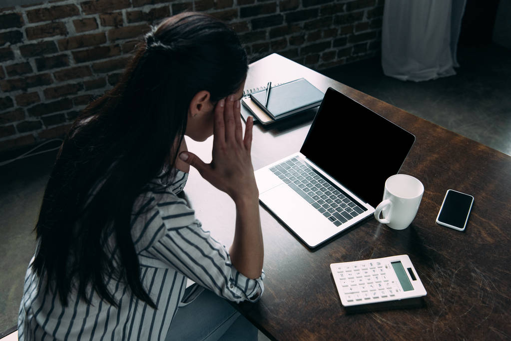 hoge hoekmening van gestresste jonge vrouw met laptop kijken hoofdpijn - Foto, afbeelding