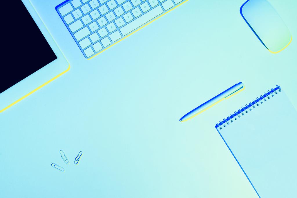 Blautöniges Bild von Büroklammern, digitalem Tablet, leerem Lehrbuch, Stift, Computertastatur und Maus  - Foto, Bild