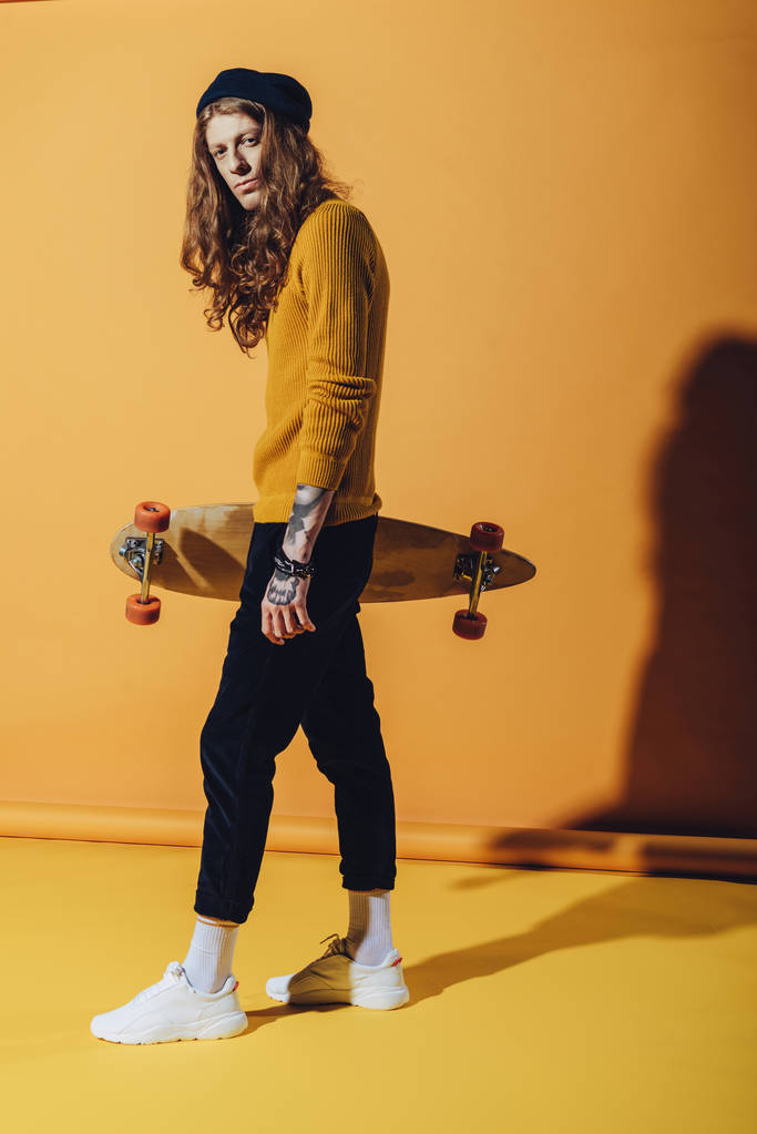 黄色のロングボードを保持しているスタイリッシュなハンサムなスケーター - 写真・画像