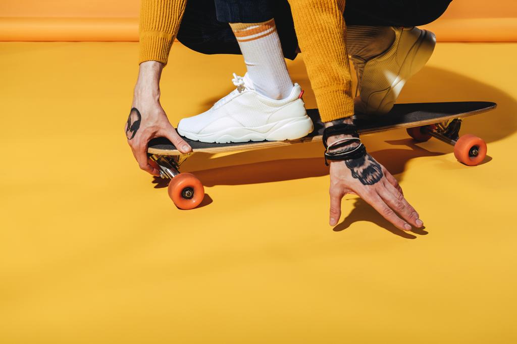 Tiefschnitt-Ansicht des Skateboarders in weißen Turnschuhen auf Longboard, auf gelb - Foto, Bild