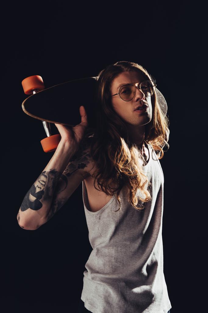 fashionable man posing with skateboard, isolated on black - Photo, Image