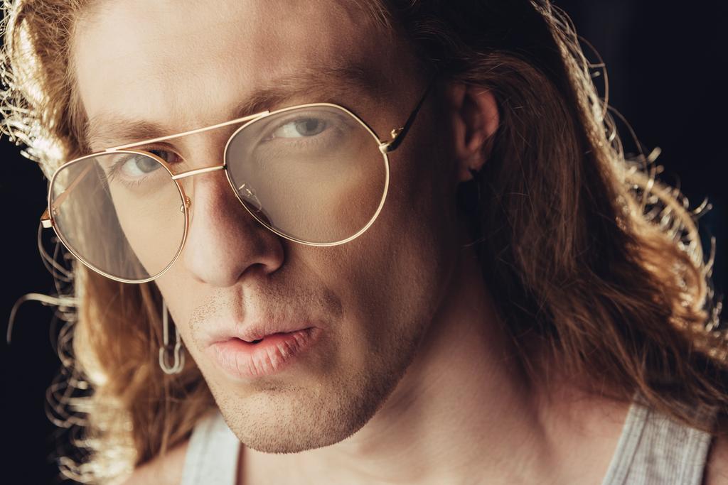 portrait of fashionable man with long hair in trendy glasses, isolated on black - Photo, Image