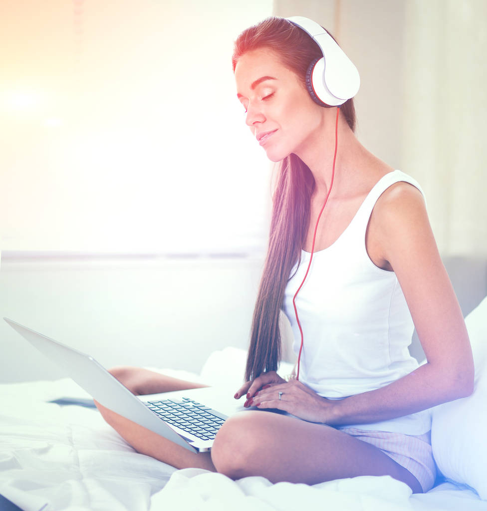 Jonge mooie vrouw in bed luisteren naar muziek - Foto, afbeelding