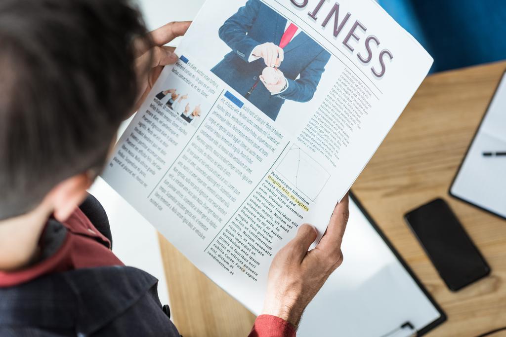 высокий угол зрения бизнесмена, читающего газету в офисе
 - Фото, изображение